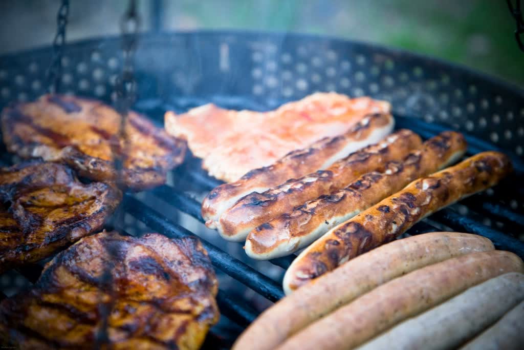 Pølser og kjøtt på grillen, nærbilde.